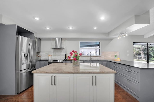 kitchen featuring backsplash, wall chimney exhaust hood, stainless steel appliances, and a center island