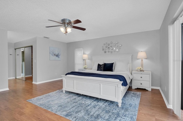 bedroom with a textured ceiling, ceiling fan, and wood-type flooring