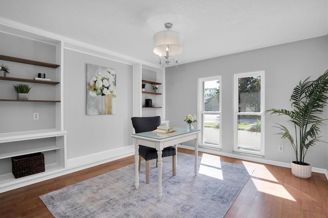 office featuring built in features, an inviting chandelier, a textured ceiling, and hardwood / wood-style floors