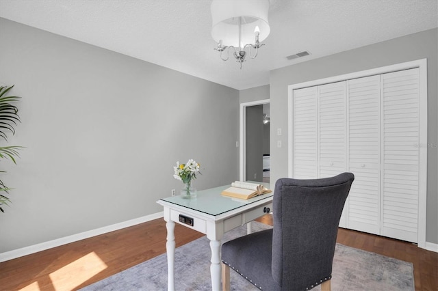 office area with a textured ceiling, dark hardwood / wood-style floors, and a notable chandelier