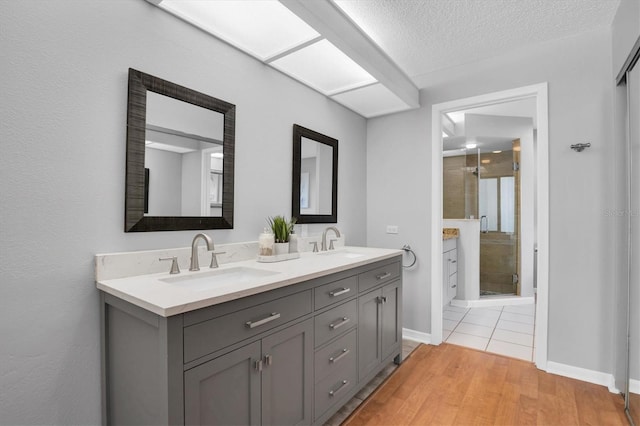 bathroom with a textured ceiling, walk in shower, vanity, and hardwood / wood-style floors