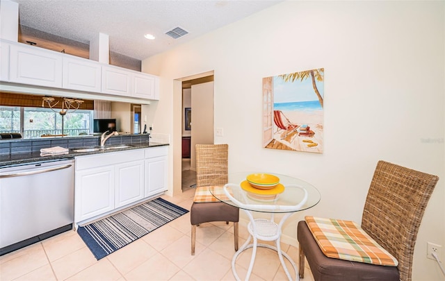 kitchen with stainless steel dishwasher, light tile patterned flooring, white cabinets, and sink