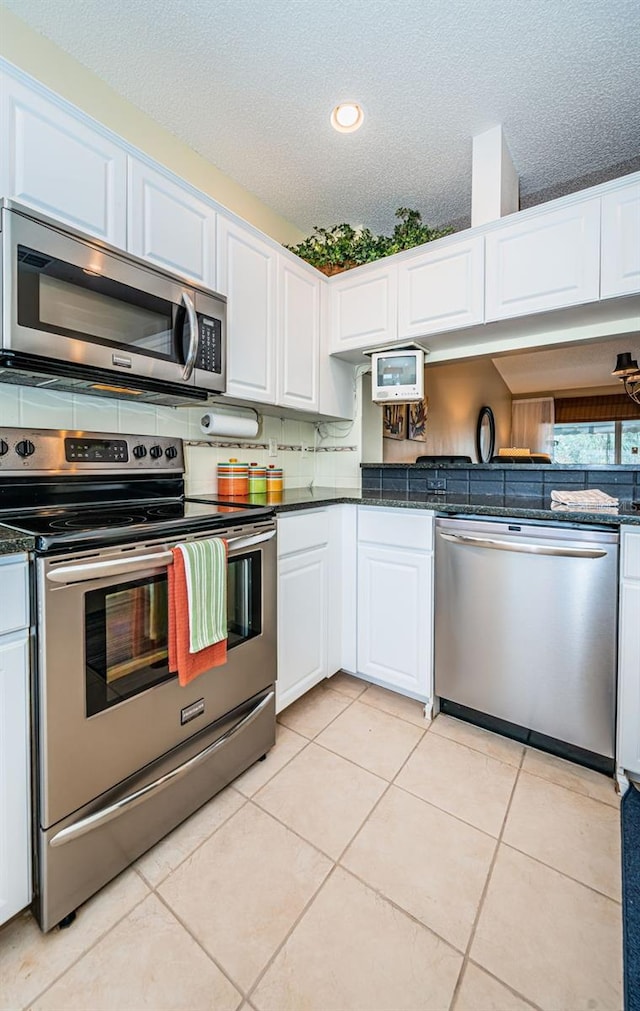 kitchen with white cabinets, a textured ceiling, stainless steel appliances, and light tile patterned flooring