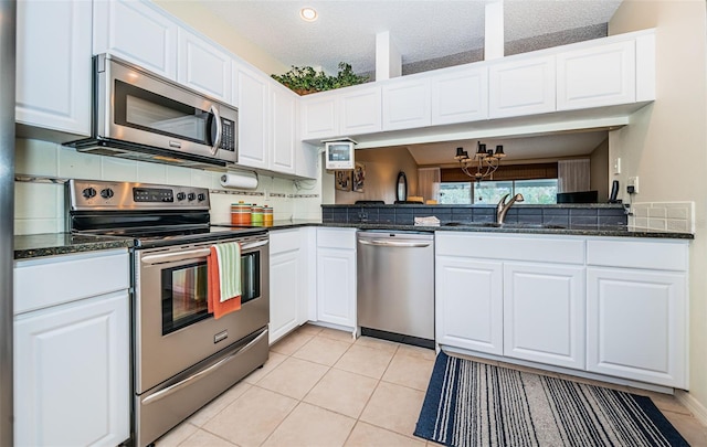 kitchen with white cabinets, light tile patterned floors, stainless steel appliances, and sink