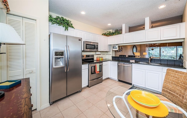 kitchen with light tile patterned flooring, stainless steel appliances, white cabinetry, and sink