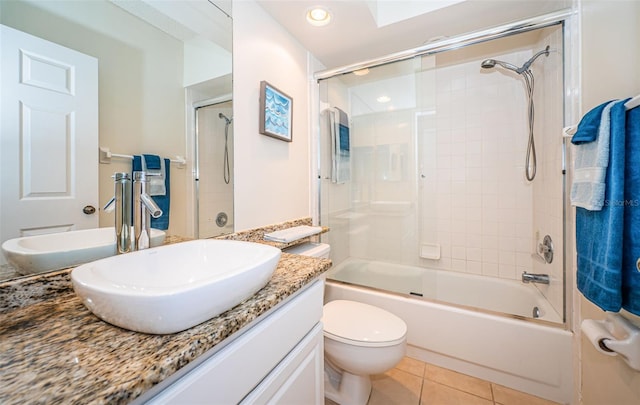 full bathroom with a skylight, tile patterned floors, bath / shower combo with glass door, toilet, and vanity