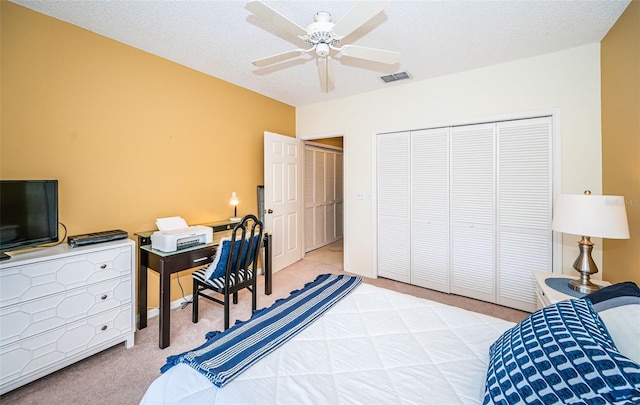 carpeted bedroom featuring ceiling fan, a textured ceiling, and a closet