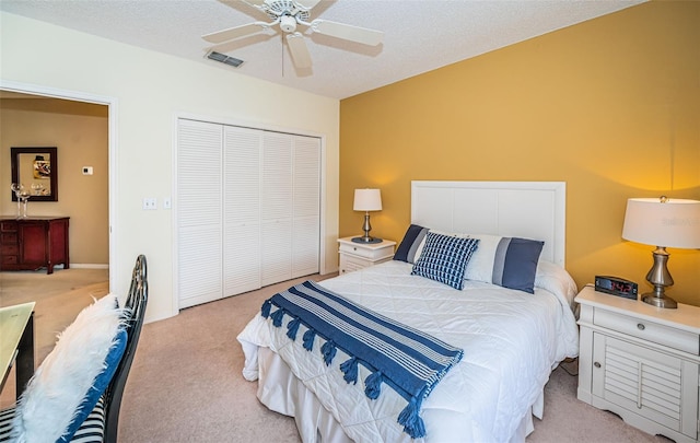 carpeted bedroom featuring a textured ceiling, a closet, and ceiling fan