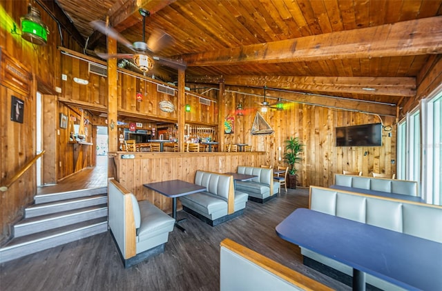 interior space featuring beam ceiling, wooden walls, and a healthy amount of sunlight