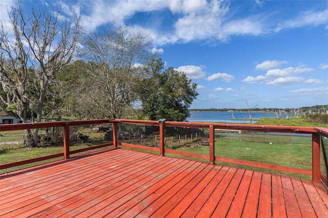 wooden terrace featuring a water view and a lawn