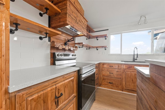 kitchen with sink, crown molding, light wood-type flooring, stainless steel electric range oven, and light stone counters