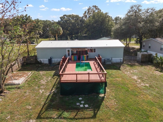 back of house with a yard, central air condition unit, and a wooden deck