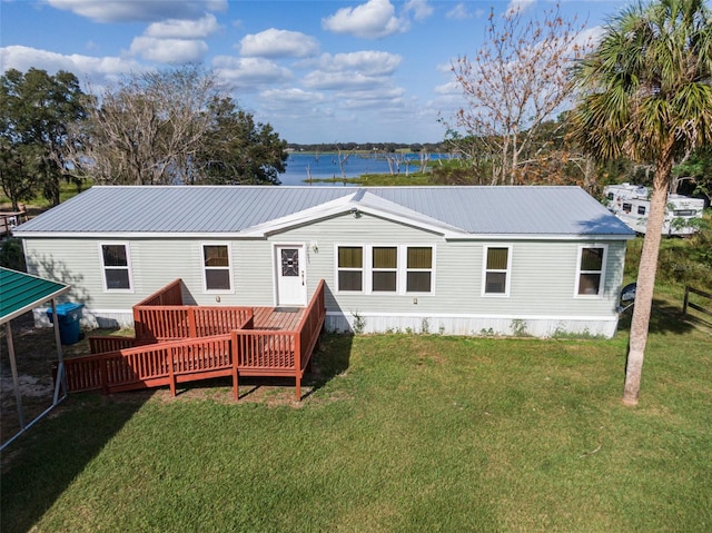 rear view of house with a lawn and a deck with water view