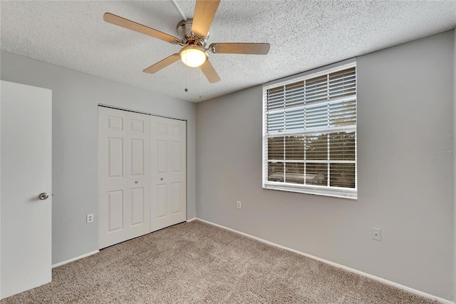 unfurnished bedroom with a textured ceiling, a closet, ceiling fan, and light colored carpet