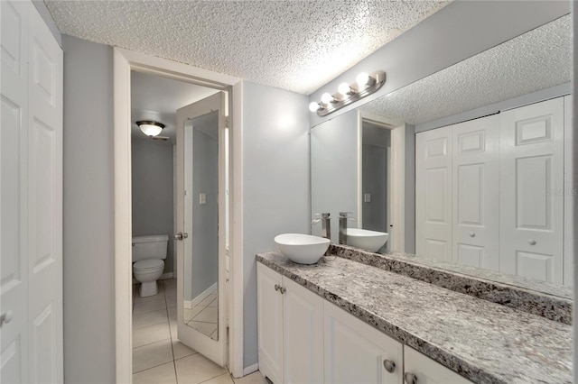 bathroom with tile patterned flooring, a textured ceiling, vanity, and toilet