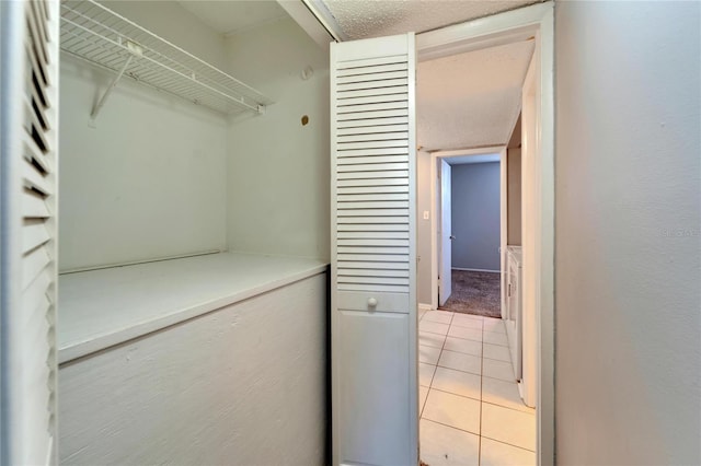 laundry room featuring light tile patterned floors and a textured ceiling