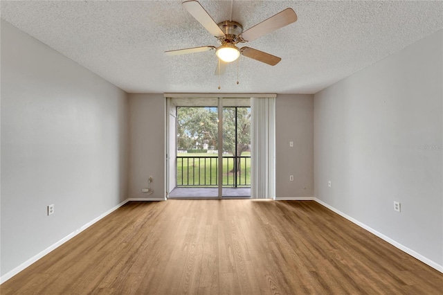 spare room with ceiling fan, floor to ceiling windows, a textured ceiling, and light hardwood / wood-style flooring