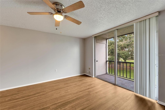 empty room with ceiling fan, floor to ceiling windows, light wood-type flooring, and a textured ceiling