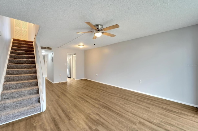 unfurnished living room featuring ceiling fan, hardwood / wood-style floors, and a textured ceiling