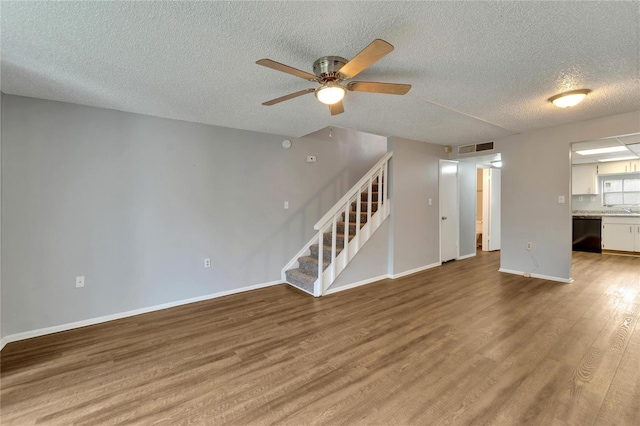 unfurnished living room with wood-type flooring, a textured ceiling, and ceiling fan