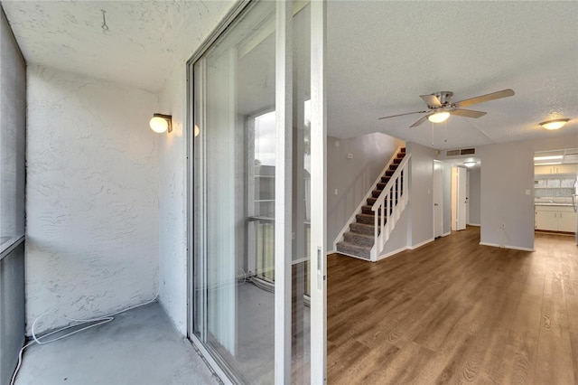 hallway with hardwood / wood-style floors and a textured ceiling