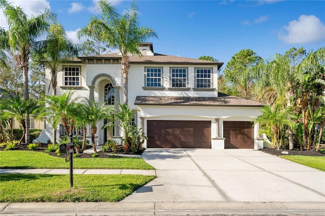 mediterranean / spanish home featuring a front yard and a garage