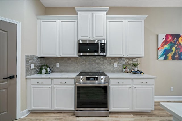 kitchen with backsplash, white cabinetry, stainless steel appliances, and light hardwood / wood-style flooring