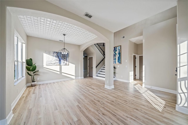 interior space with light wood-type flooring, a healthy amount of sunlight, and a notable chandelier