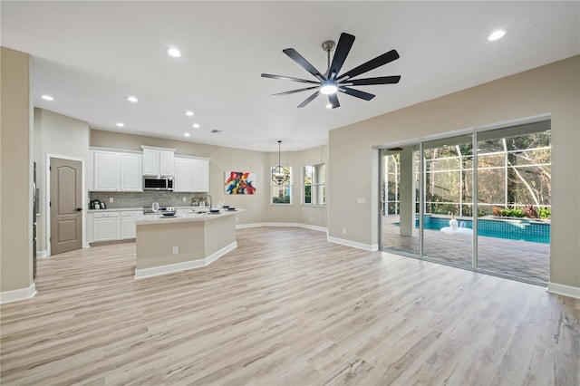 kitchen featuring stainless steel appliances, light hardwood / wood-style flooring, white cabinetry, and a healthy amount of sunlight