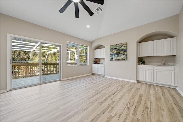 unfurnished living room featuring ceiling fan, sink, light hardwood / wood-style flooring, and vaulted ceiling