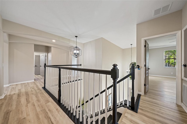 hallway with light hardwood / wood-style flooring and a chandelier