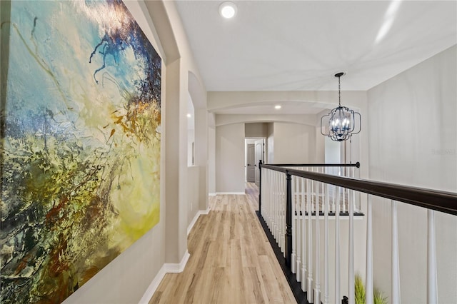 hallway featuring light wood-type flooring and an inviting chandelier