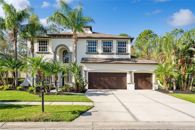 mediterranean / spanish-style home featuring a garage and a front lawn