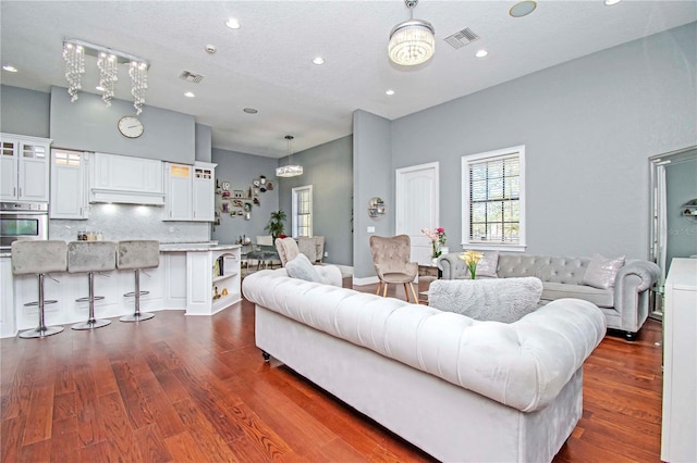 living room with dark hardwood / wood-style flooring, a textured ceiling, and a chandelier