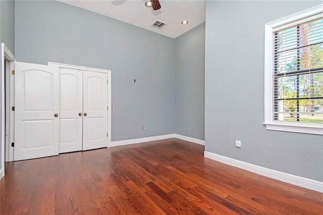 unfurnished bedroom featuring ceiling fan, dark hardwood / wood-style floors, and a closet