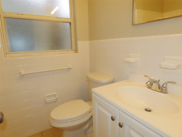 bathroom featuring vanity, toilet, and tile walls