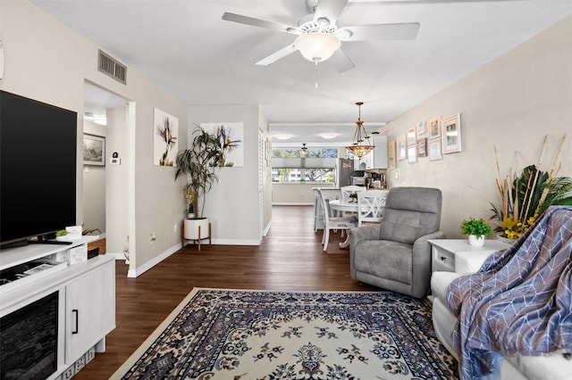 living room with ceiling fan with notable chandelier and dark hardwood / wood-style flooring