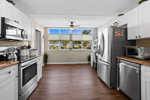 kitchen with dark stone countertops, white cabinetry, dark wood-type flooring, and stainless steel appliances