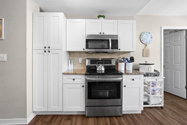 kitchen featuring appliances with stainless steel finishes, dark hardwood / wood-style floors, white cabinetry, and dark stone counters