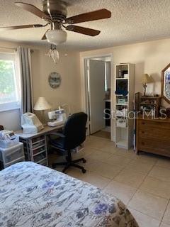 8906 Windsong Ln, Port Richey, FL 34668 - bedroom with light tile patterned floors, a textured ceiling, and a ceiling fan