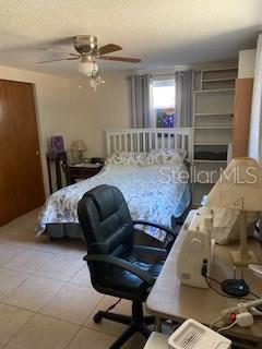 8906 Windsong Ln, Port Richey, FL 34668 - tiled bedroom featuring ceiling fan and a textured ceiling