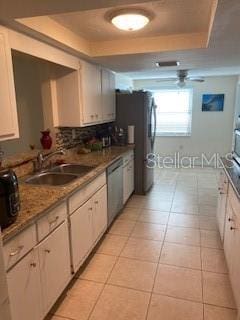 8906 Windsong Ln, Port Richey, FL 34668 - kitchen featuring a raised ceiling, dishwasher, a sink, and white cabinets