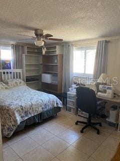 8906 Windsong Ln, Port Richey, FL 34668 - tiled bedroom with a textured ceiling and ceiling fan