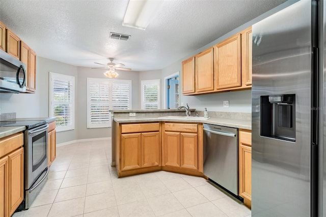 kitchen featuring sink, ceiling fan, light tile patterned floors, a textured ceiling, and appliances with stainless steel finishes