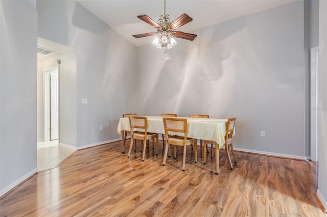 dining room with ceiling fan, vaulted ceiling, and light wood-type flooring