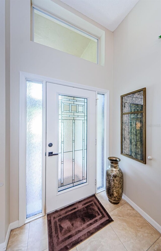 entryway with light tile patterned floors and lofted ceiling