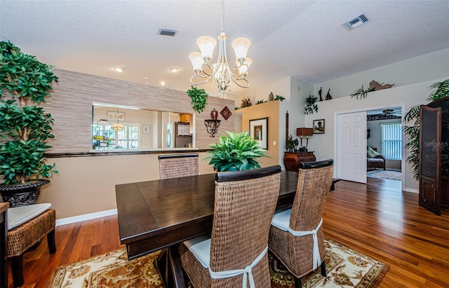 dining area featuring a textured ceiling, dark hardwood / wood-style flooring, and a notable chandelier