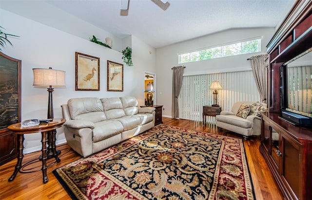 living room featuring a textured ceiling, ceiling fan, wood-type flooring, and vaulted ceiling