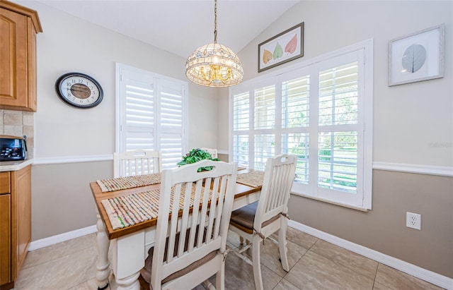 dining area with light tile patterned floors, a chandelier, and vaulted ceiling