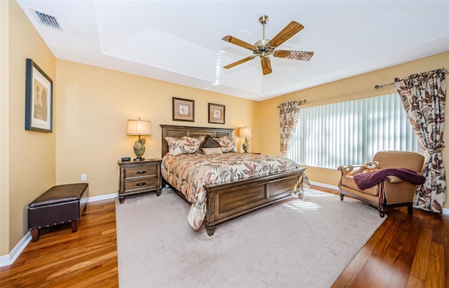 bedroom featuring hardwood / wood-style flooring, a raised ceiling, and ceiling fan